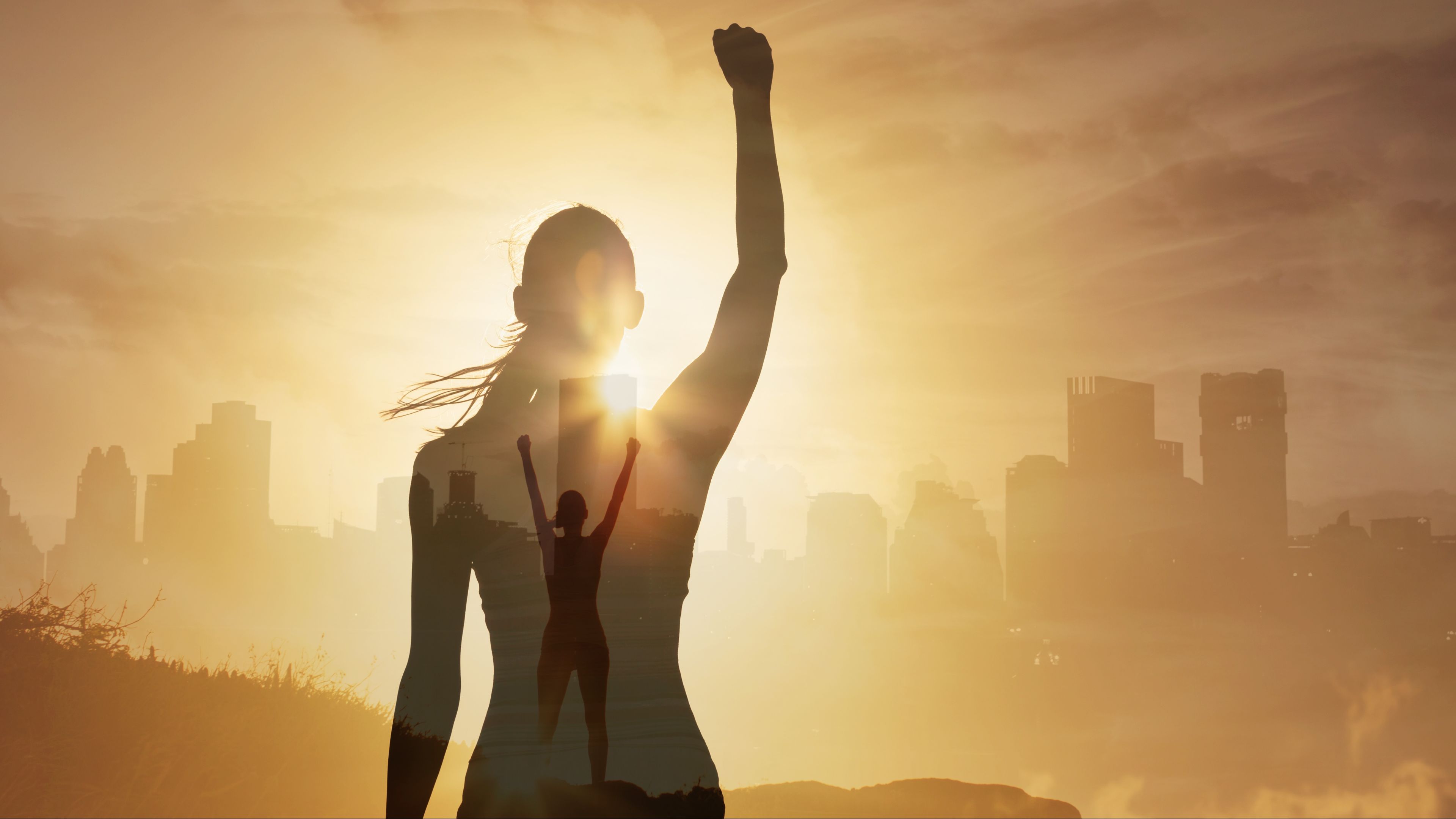 Woman with arm up in the air in the sunset