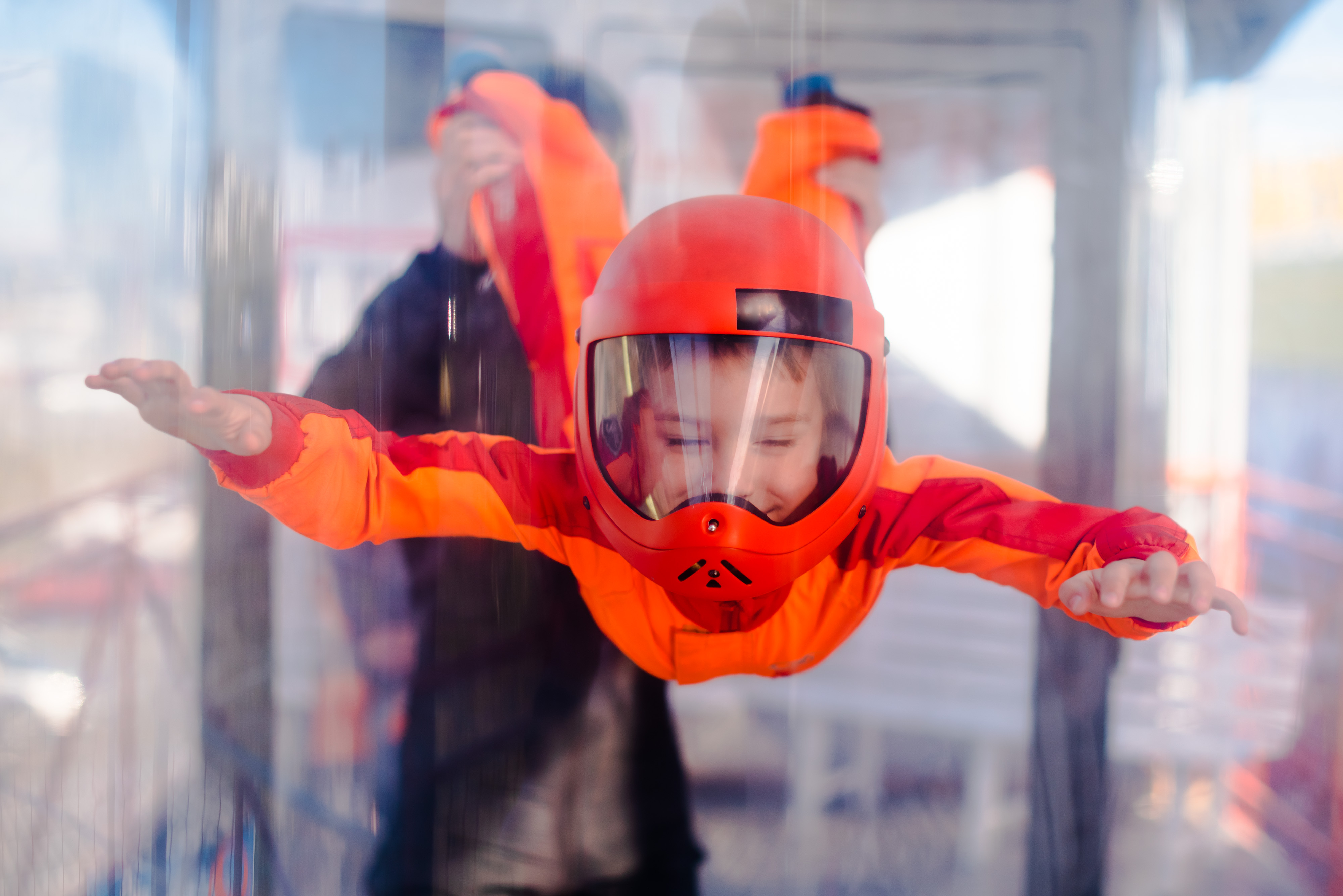 Excited boy in orange helmet flying in aerodynamic tube (wind tunnel). Skydiving training.; Shutterstock ID 1758179204; purchase_order: ; job: 11797809; client: Hertz US; other: Anastasiia