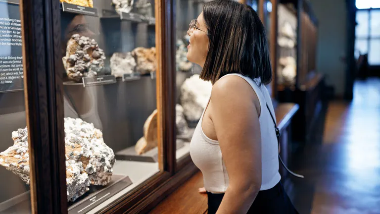 Woman looking at a case full of rocks and crystals in a museum